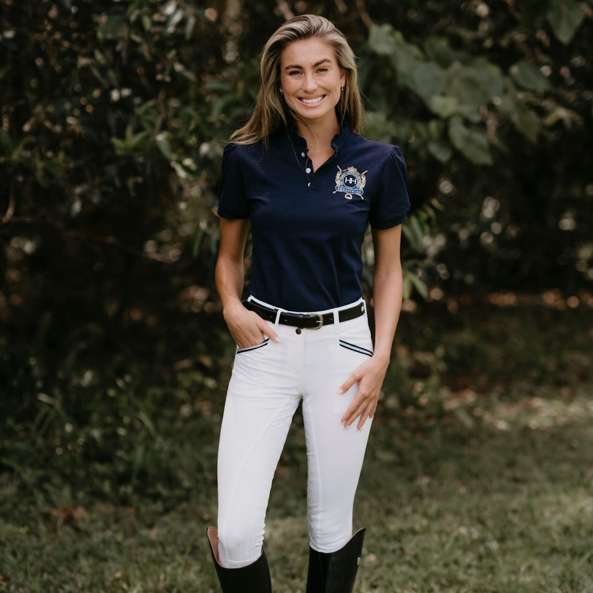 Lady wearing navy shirt with white breeches and black belt.
