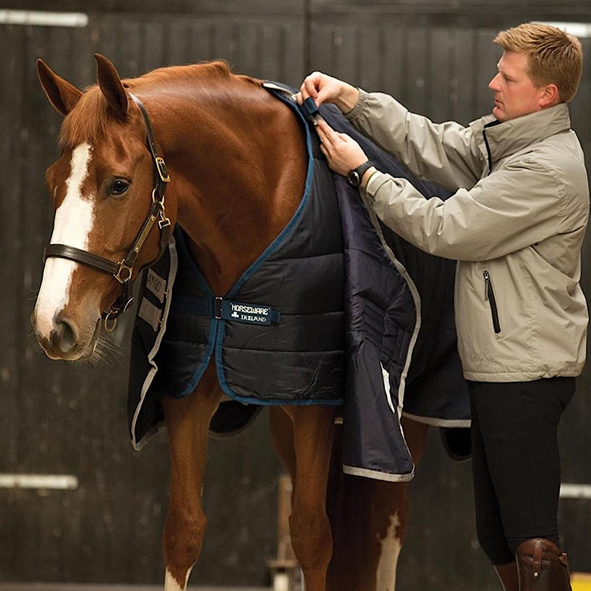 Person fixing horse&#39;s liner to top rug with front tabs.