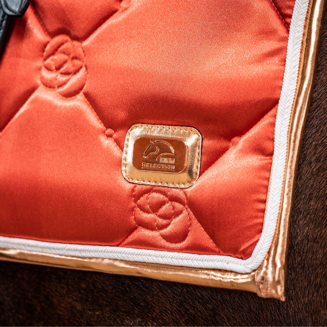 Brandy saddle pad close up, of HKM rose gold logo.