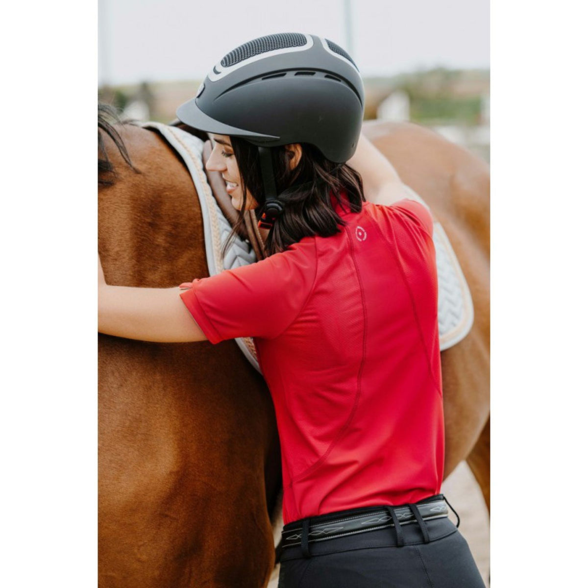Lady wearing the bright cherry red polo with black breeches and a black leather belt