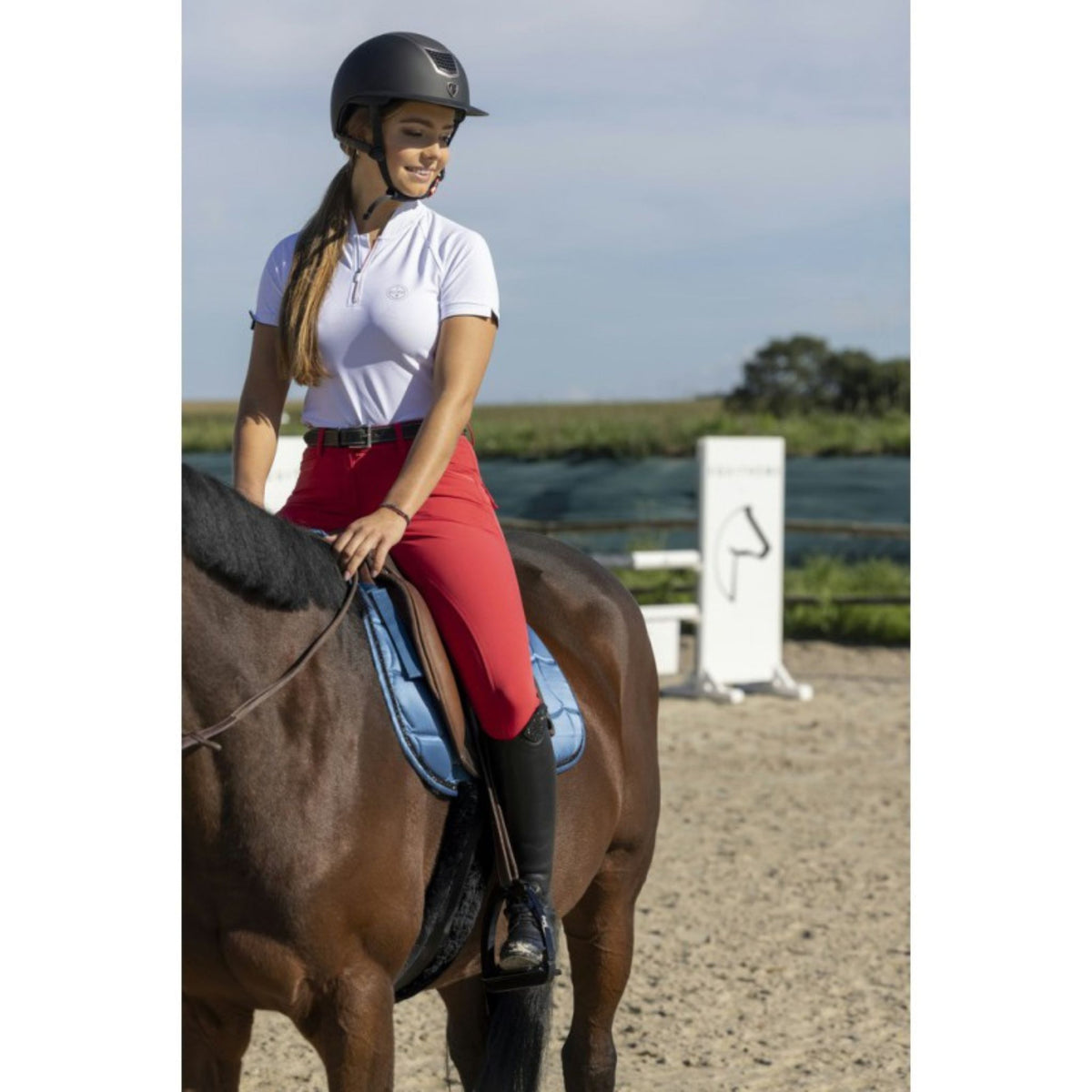 Lady riding in the white polo with red breeches on.