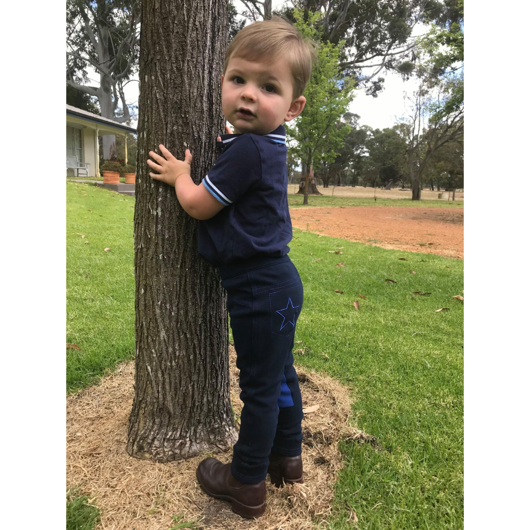 small boy dressed in blue hugging a tree