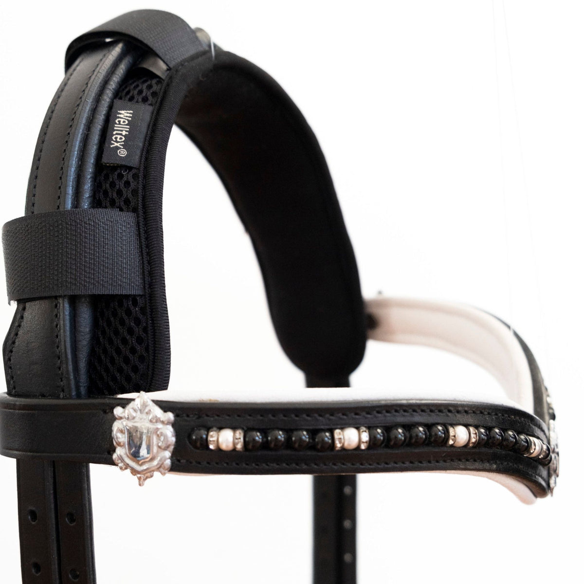 Black poll cover attached to the crownpiece of a bridle. 