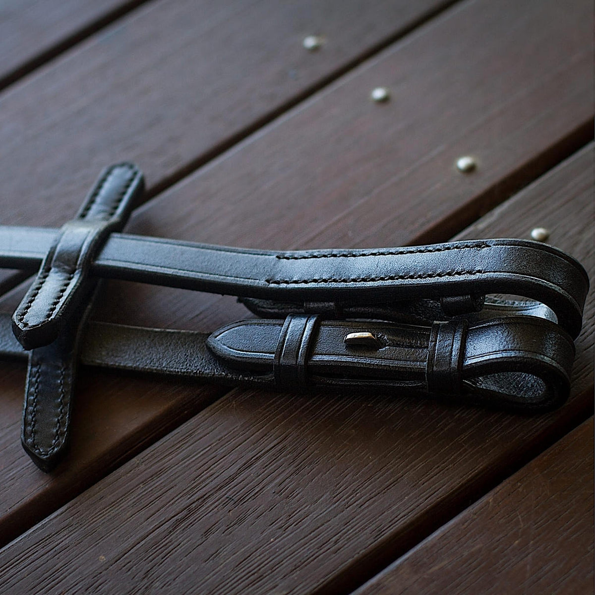 Close up of black leather reins, showing stoppers for rings.