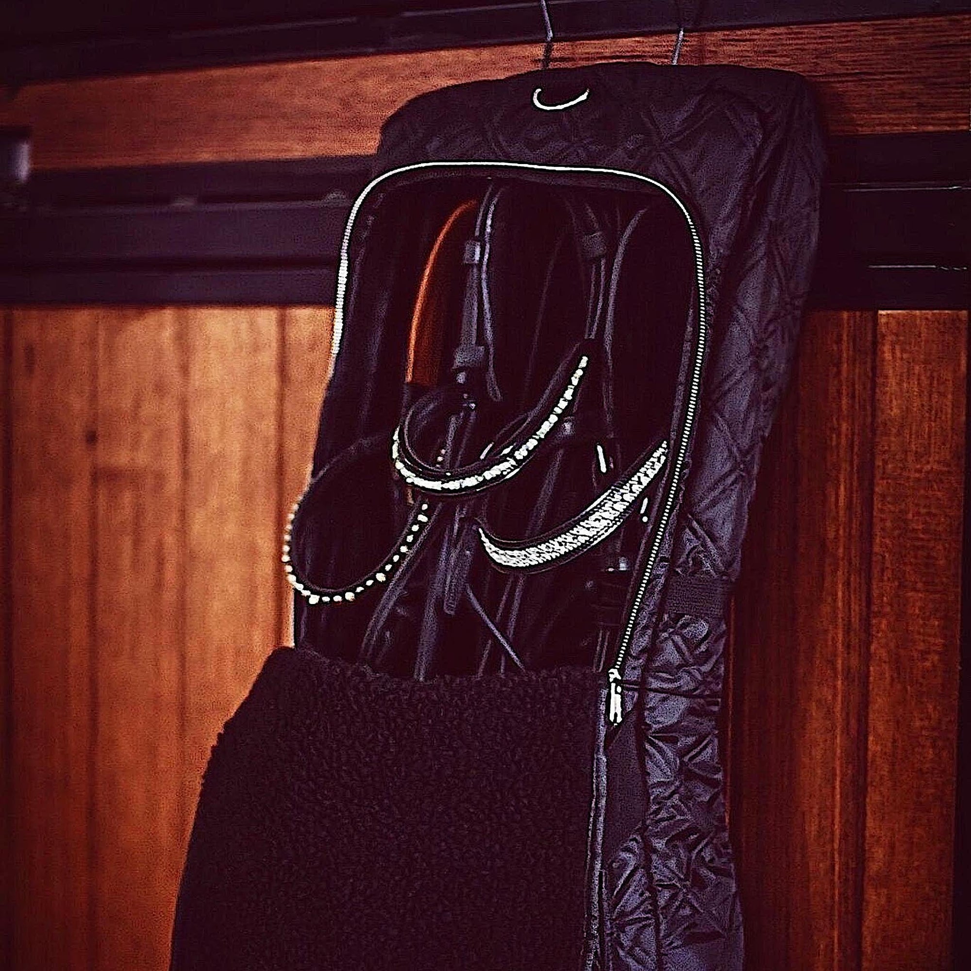 Three bridles hanging in black bridle bag with a fleece interior.