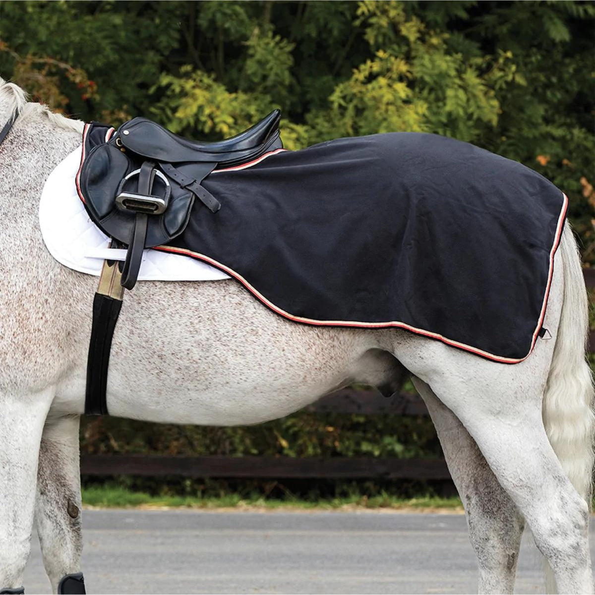 Black ridding rug with tan, orange and black binding on grey horse