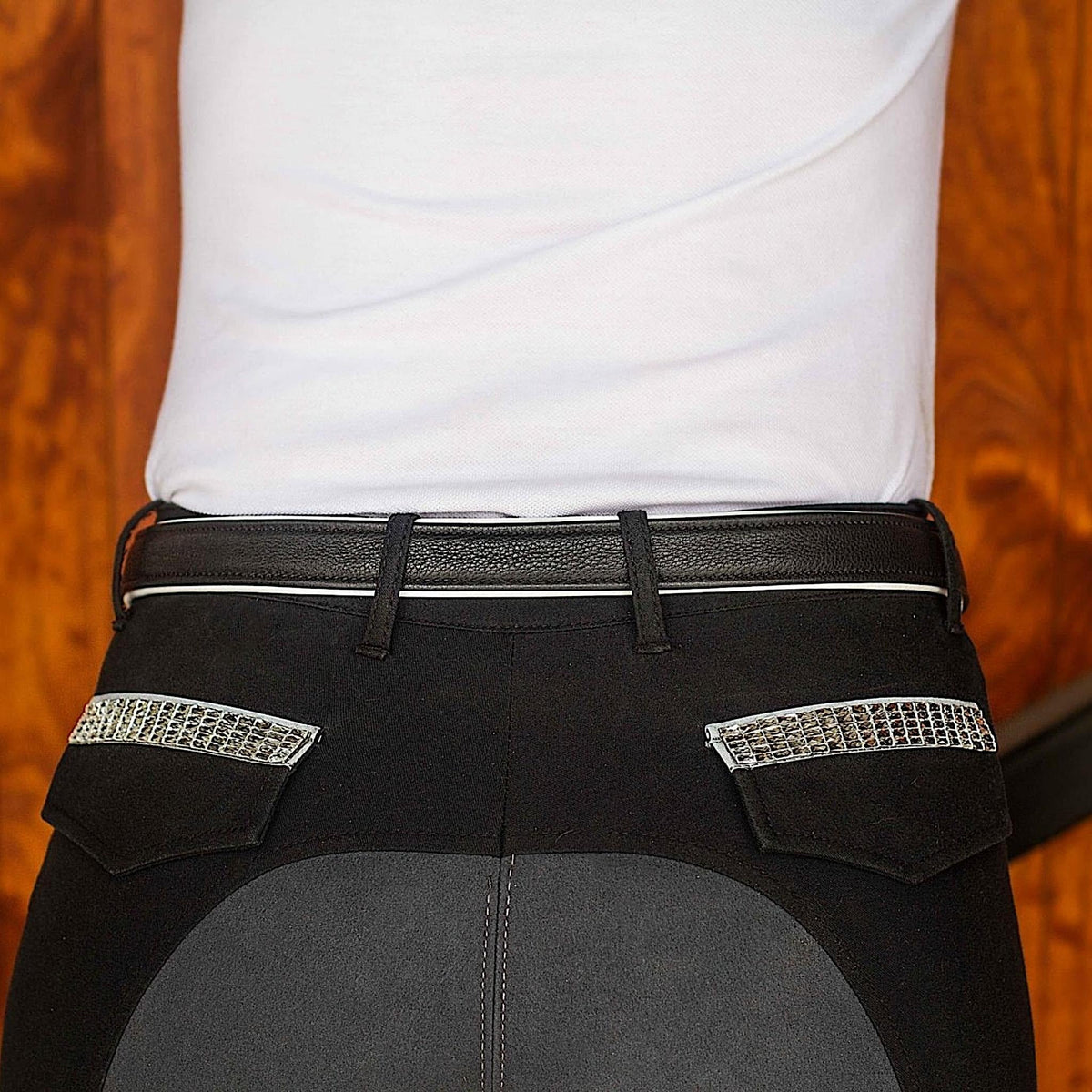Black leather belt with white padding visible on edges, on black jodhpurs.