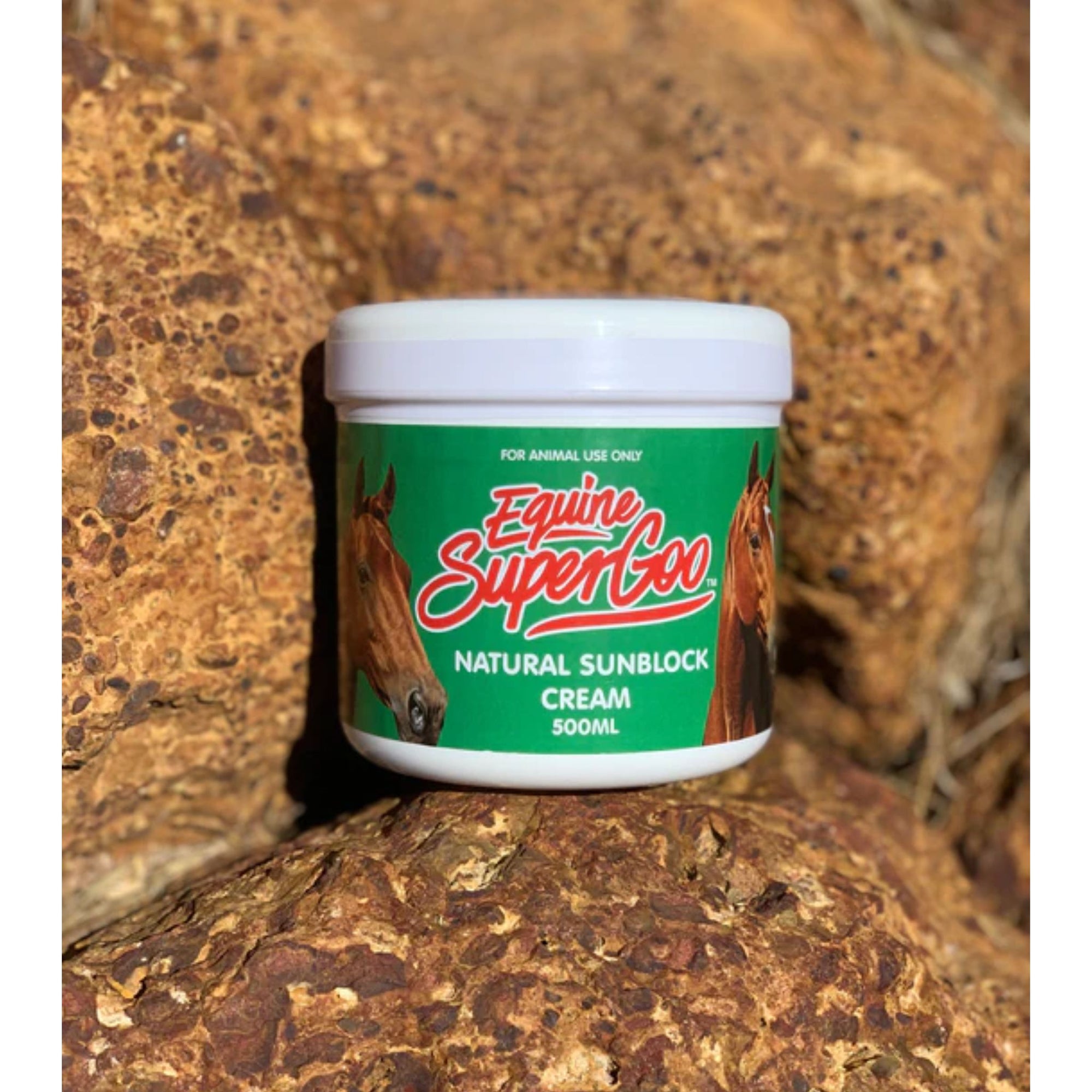 Tub of "SuperGoo" sunblock with green label, nestled in rocks.
