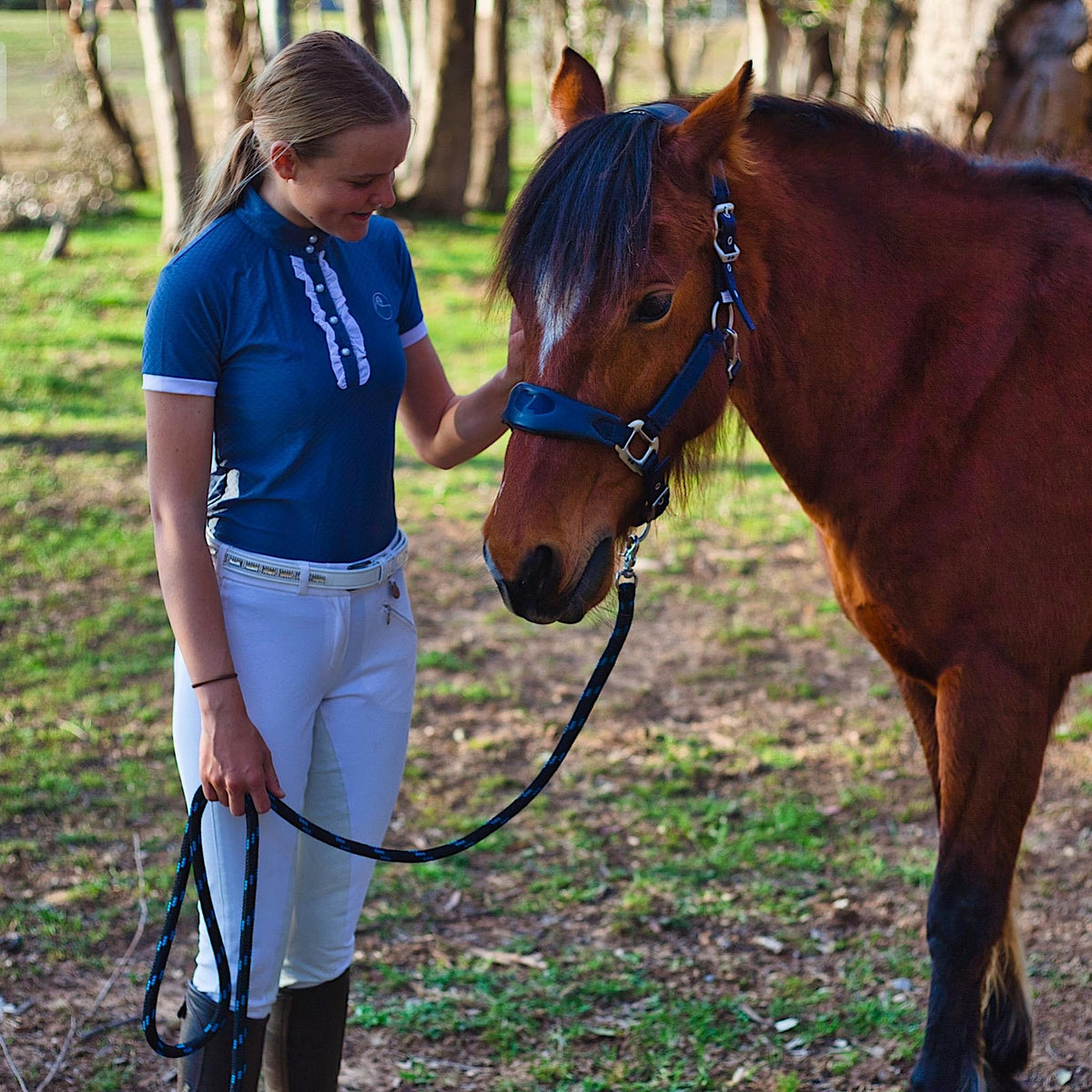 Lady holding horse, whilst wearing grey show shirt with white details.