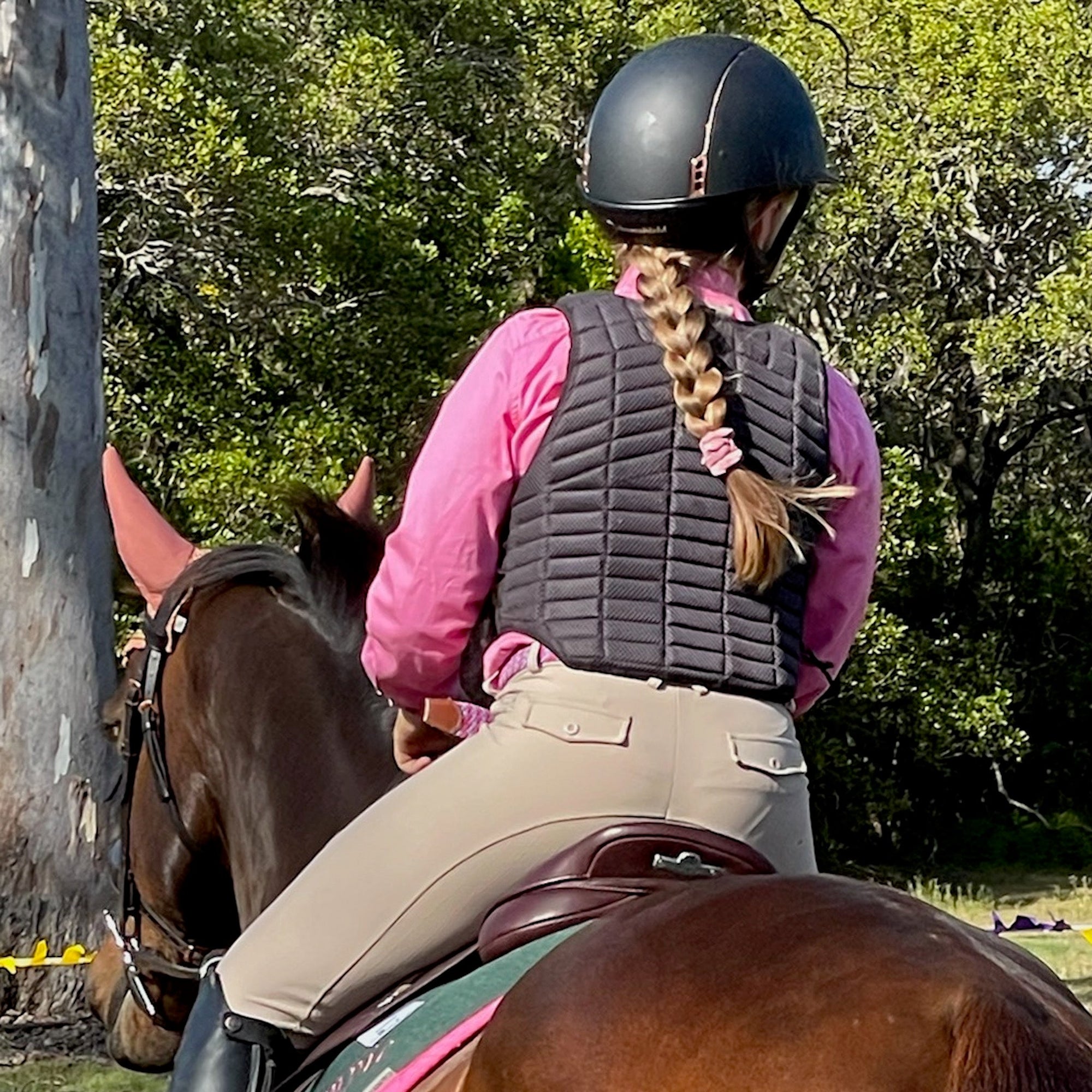 Girl riding horse, wearing beige riding tights with back pockets.