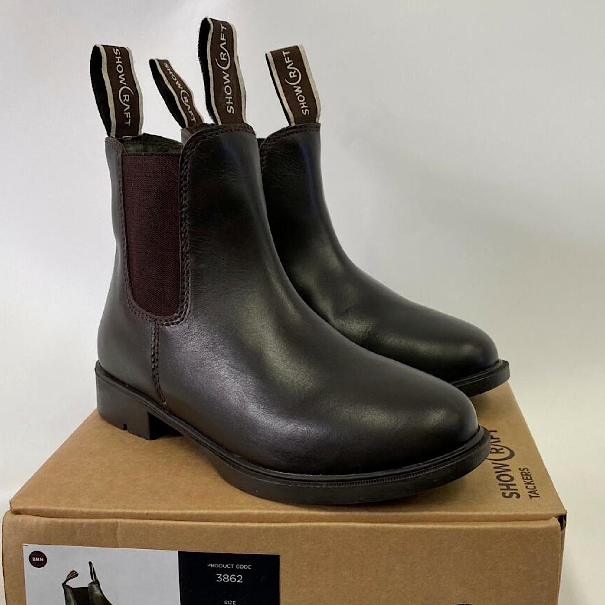Brown leather boots with front and back pull tabs, on a box.