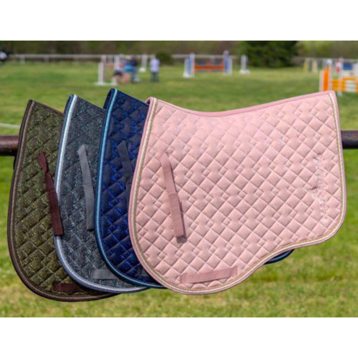 Four glitter saddle pads along a fence in various colours.