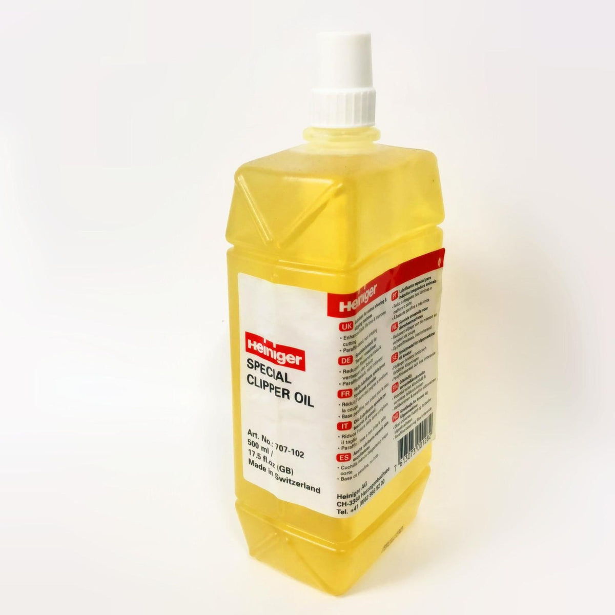 Transparent bottle of yellow oil with red and white label.
