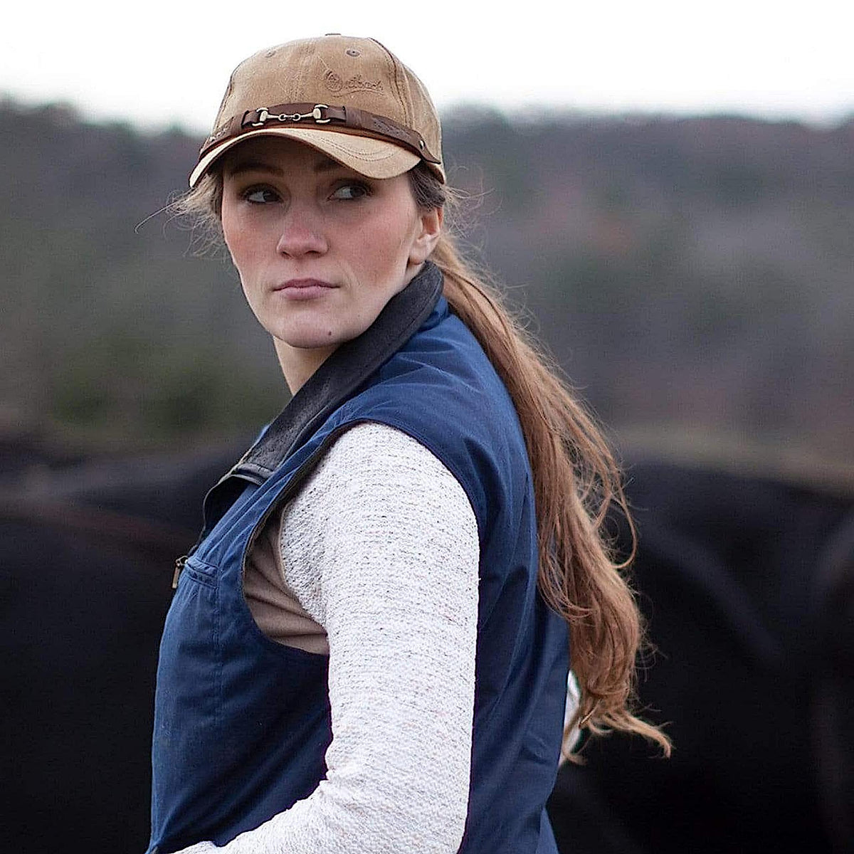 A woman wearing the tan equestrian cap.