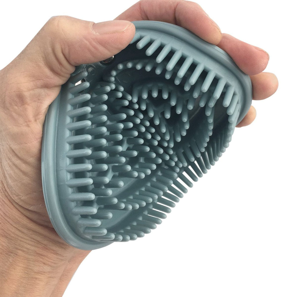 Hand holding light blue rubber curry comb in flexed position.