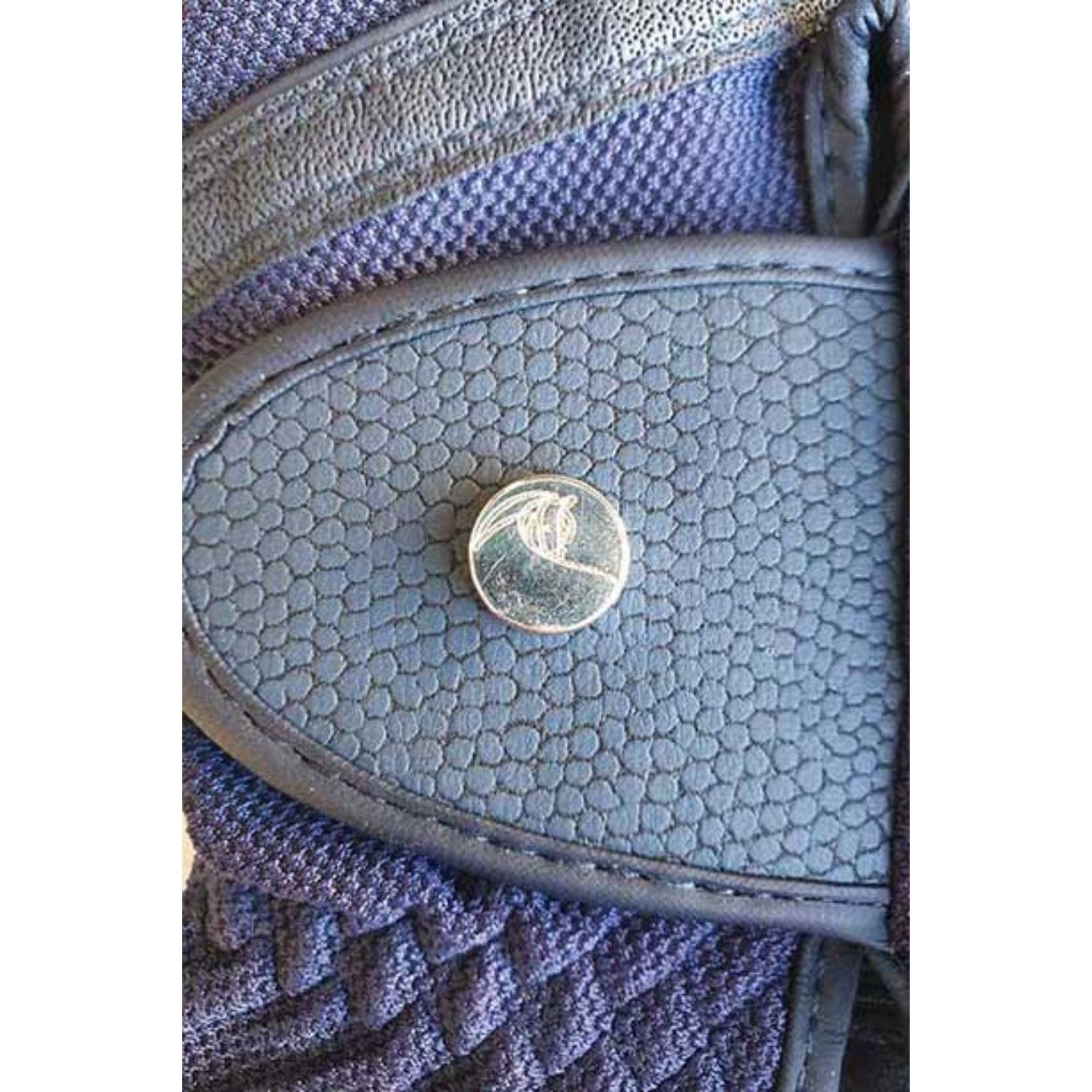 Navy mesh riding gloves on hand, with subtly patterned leather detailing.