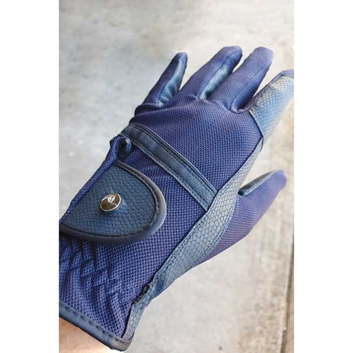 Navy mesh riding gloves on hand, with subtly patterned leather detailing.