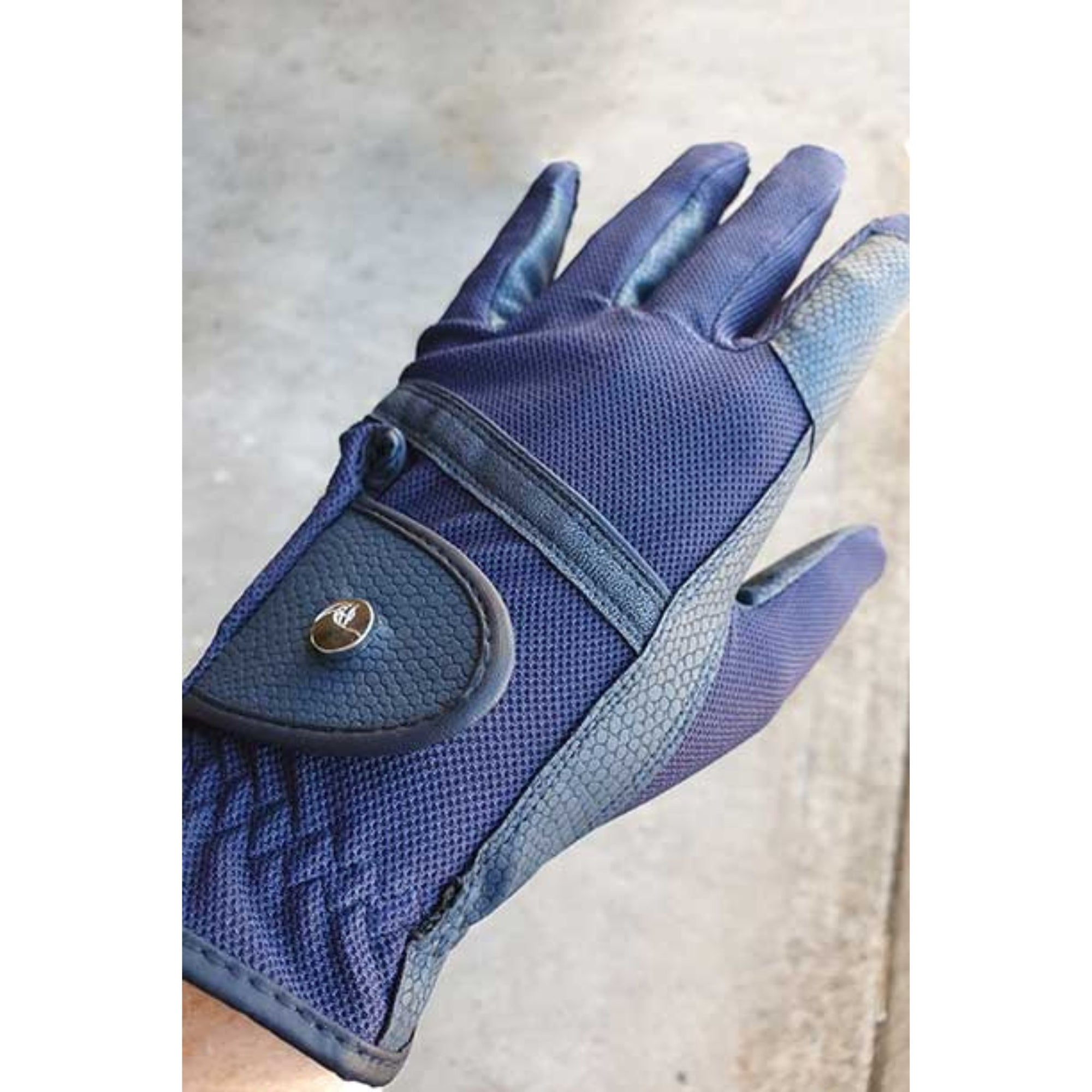 Navy mesh riding gloves on hand, with subtly patterned leather detailing.